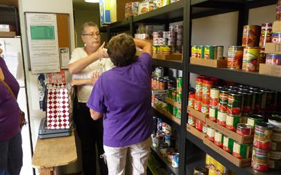 Kelly and Donna work side by side to provide food for clients.